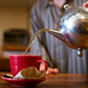 Man pours tea from kettle into mug